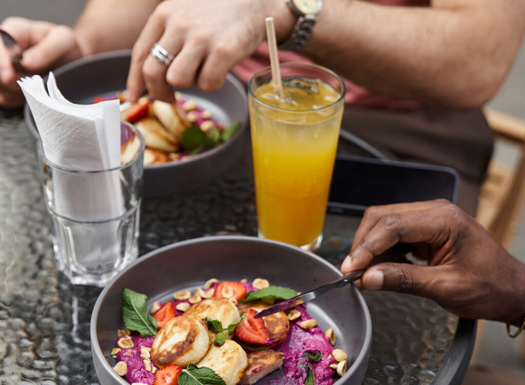 Close up photo of friends enjoying lunch at an outdoor restaurant.